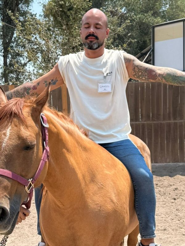 un hombre montando un caballo en un campo de tierra
